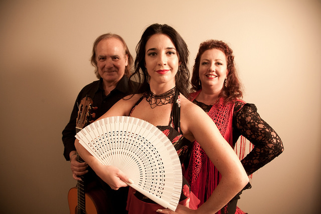 photograph of 3 people in dance costume. Woman in front with white fan