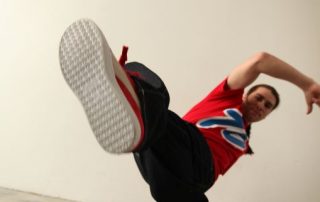 photo of young man wearing red t-shirt and red running shoes in a hip-hop dance pose