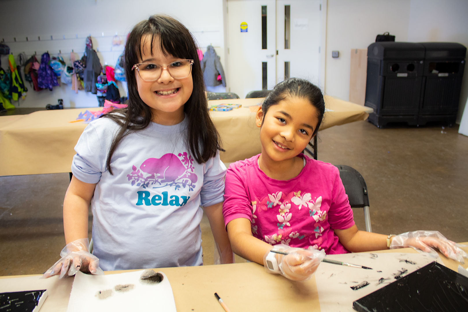 Two children working on art projects at a table with supplies