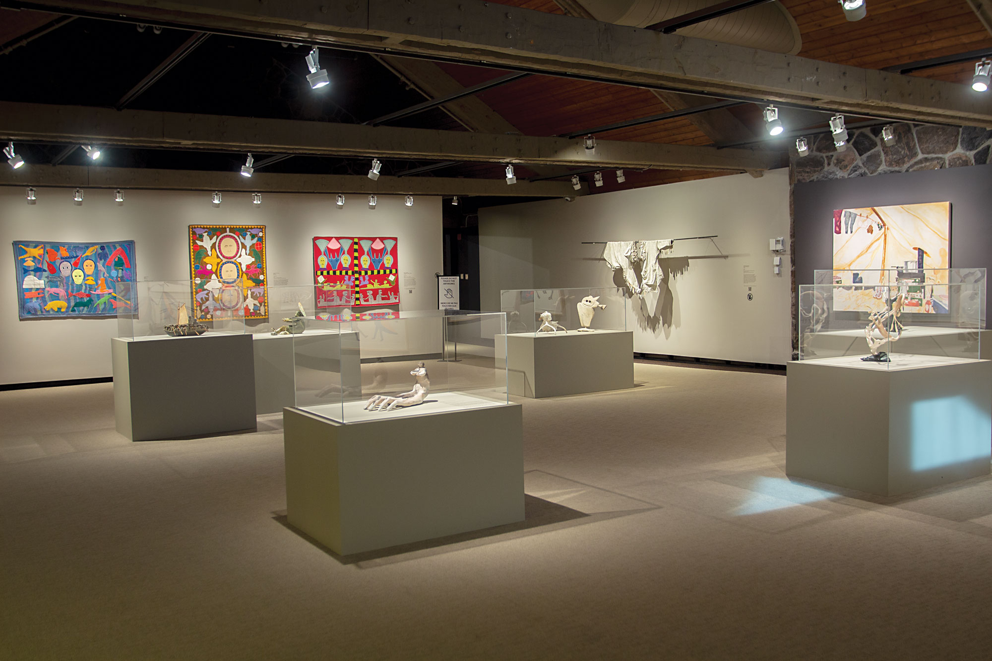 Spacious gallery interior with abstract artworks and central display cases.