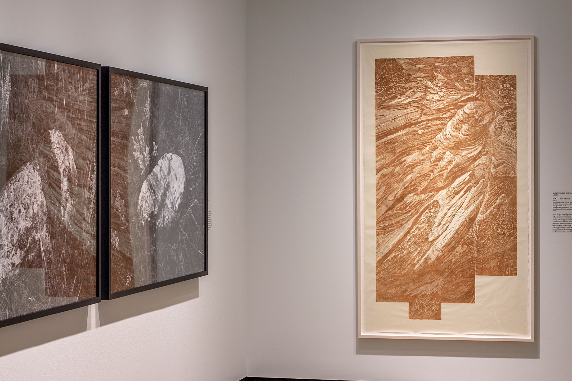 Gallery wall corner featuring large black-and-white and sepia artworks.
