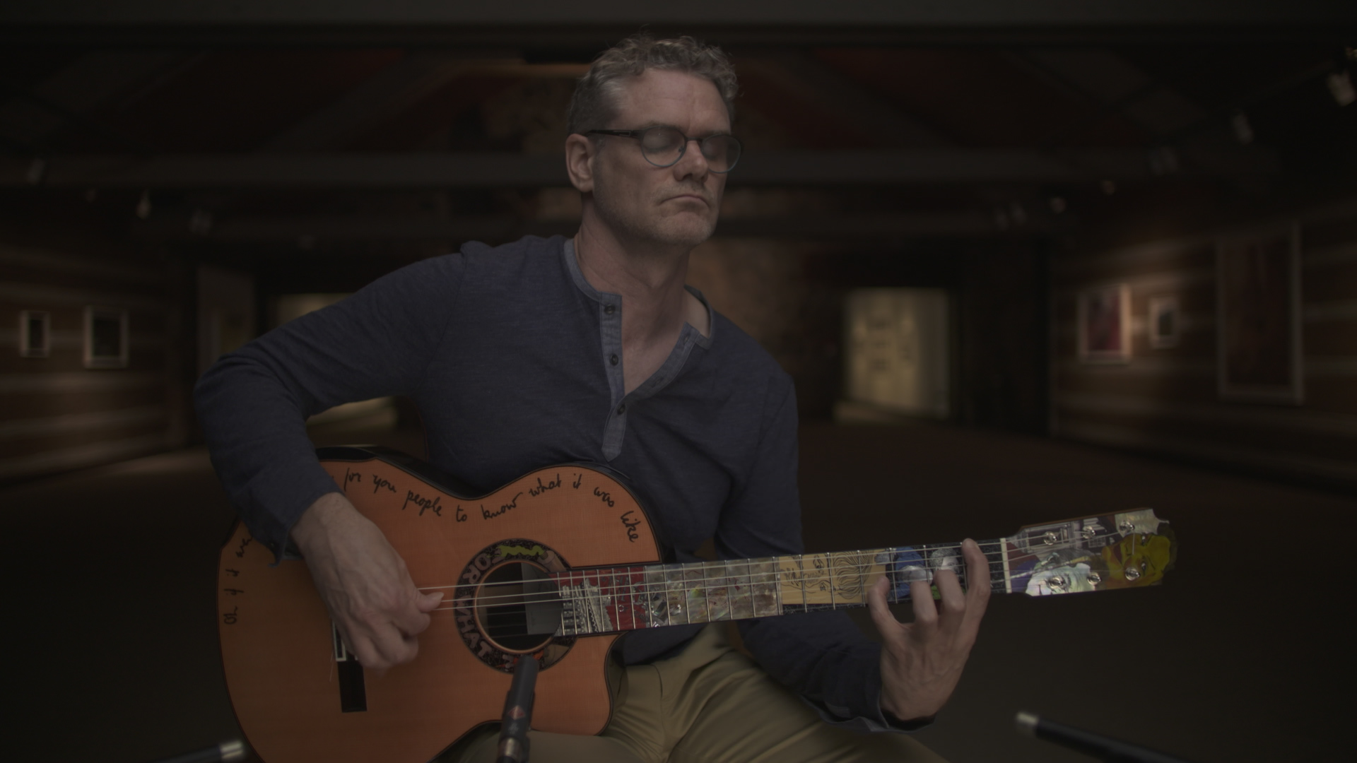 Jesse playing a guitar made by Sergi de Jonge, inspired by the works of J.E.H. MacDonald, 2016, Courtesy of Riddle Films, McMichael Canadian Art Collection