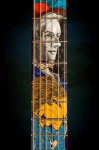 photo pf the neck of a guitar with the image of a man inlaid in the wood