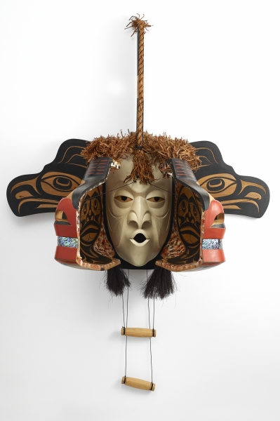 image of a wooden mask with human head in centre flanked by animal and bird heads