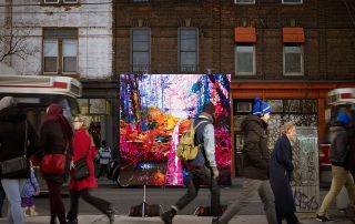 photograph of a landscape painting on a stand in a city street. People walking by on sidewalk and a streetcar