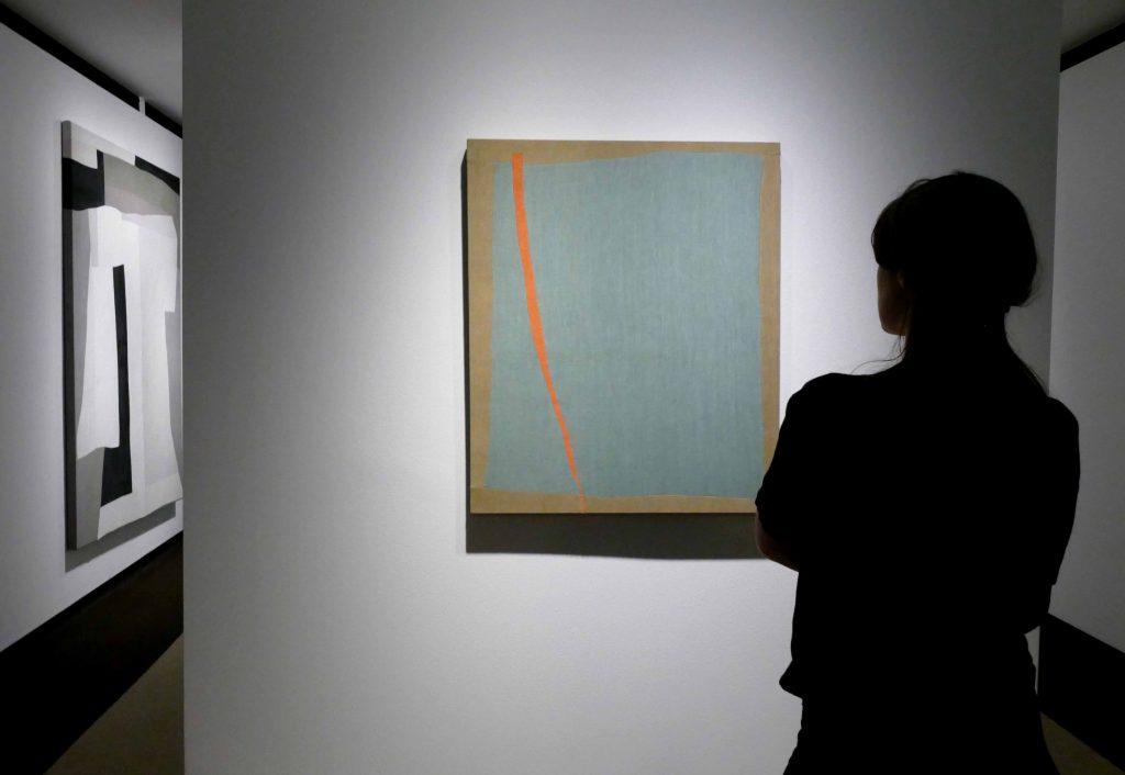 Colleen Heslin, Seafoam photograph of a woman looking at art on gallery wall
