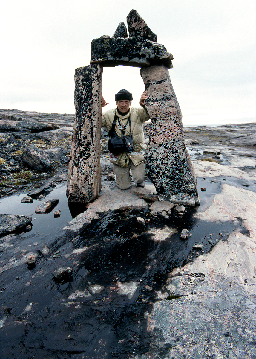 photo of man kneeling in stone archway in rocky landcsape